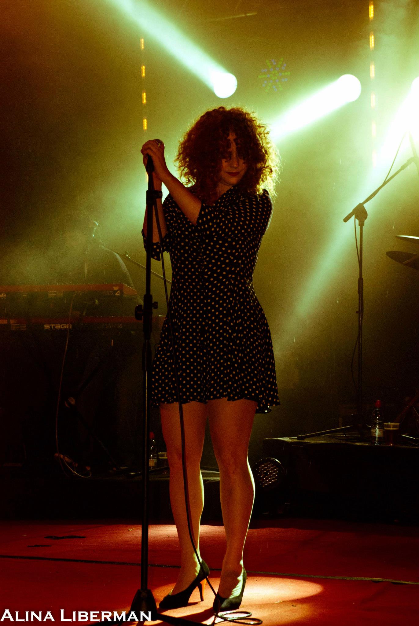 Noa at the microphone under golden stage lights