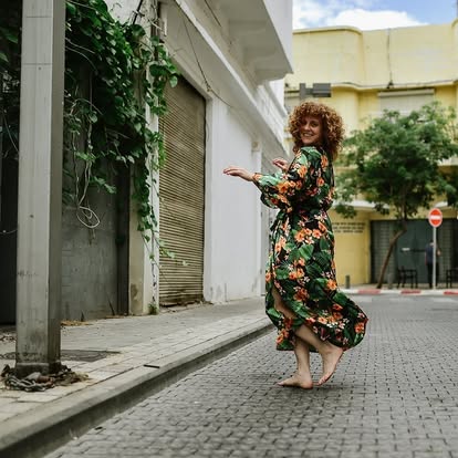 Noa barefoot on a cobblestone street in a floral dress